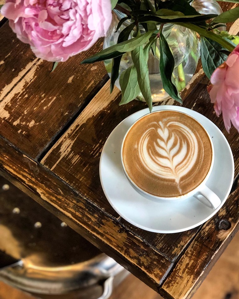 A latte with flowers on a rustic table